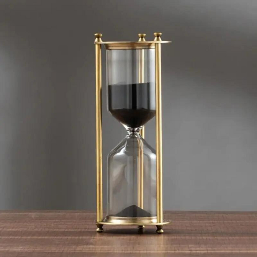 Antique hourglass made of brass with violet sand