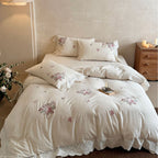 Embroidered cotton-linen bedding set with rose motifs, lace ruffle, and natural texture