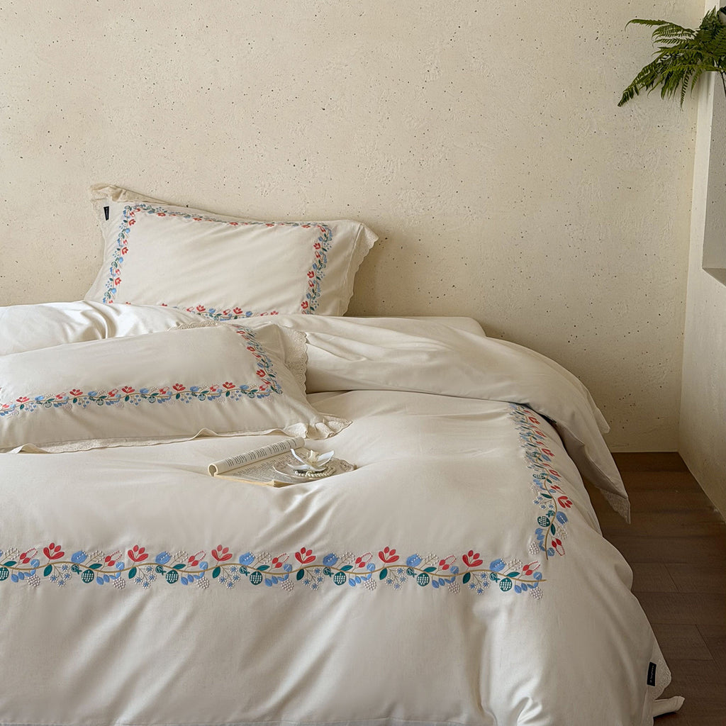 Embroidered cotton satin bed linen set with floral border and fine lace edge