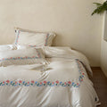 Embroidered cotton satin bed linen set with floral border and fine lace edge