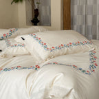 Embroidered cotton satin bed linen set with floral border and fine lace edge
