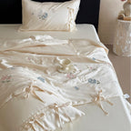 Satin bedding set with floral embroidery, tie ribbons, and silky glossy finish